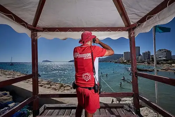 Socorrista observando la playa con prismáticos